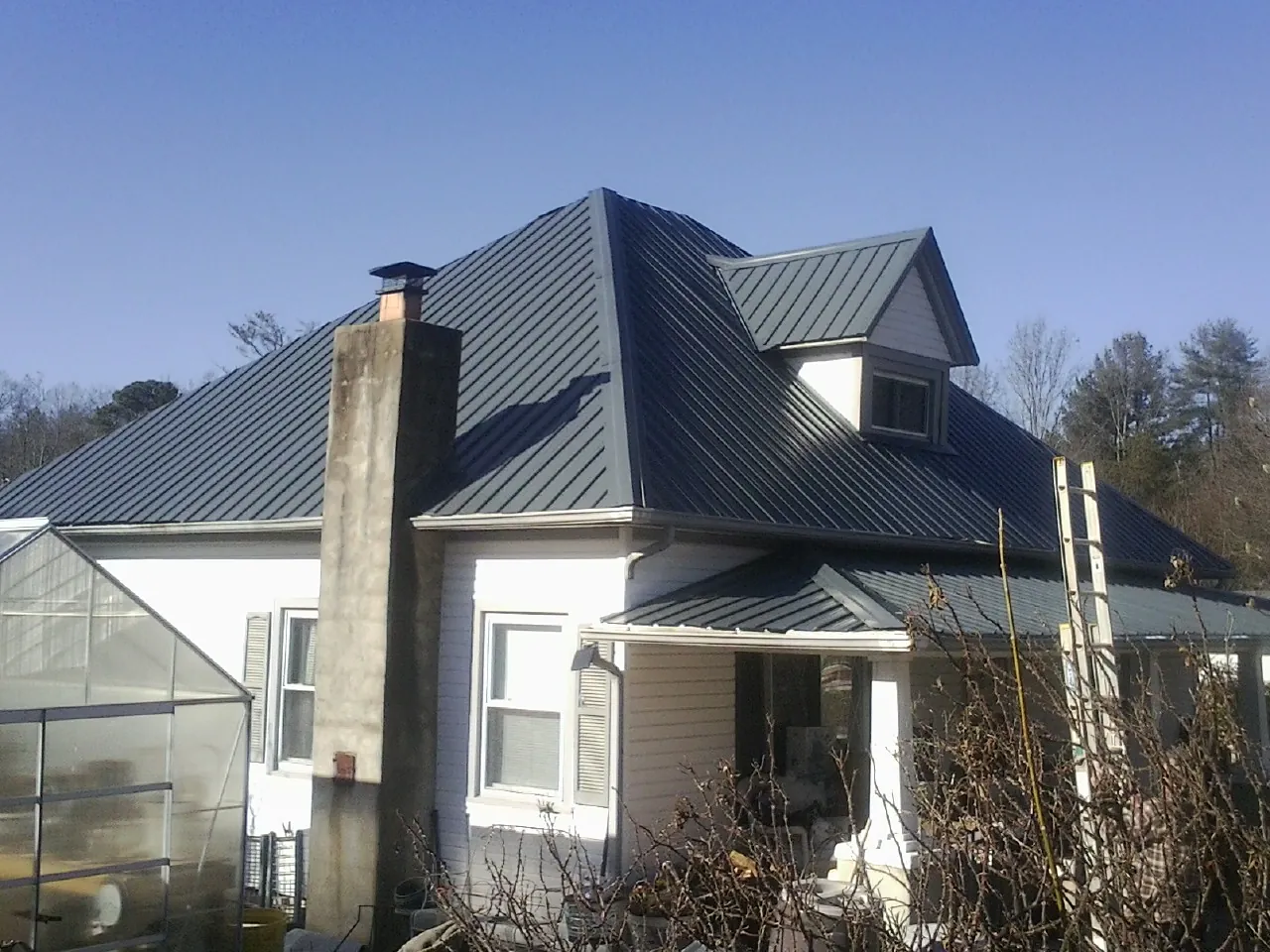 Dark blue standing seam metal roof on a white farmhouse with dormer — Slate & Tile Roof Repair by Roofing Brothers in Hooks