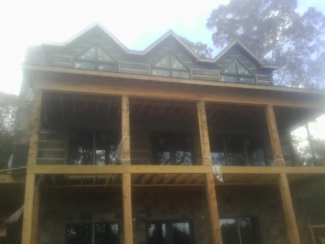 Dormers and porch framing on a large log home under construction — Roof Coating work by our crew in Hooks