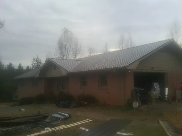 Gray metal roof on a stucco house with an attached garage in Hooks