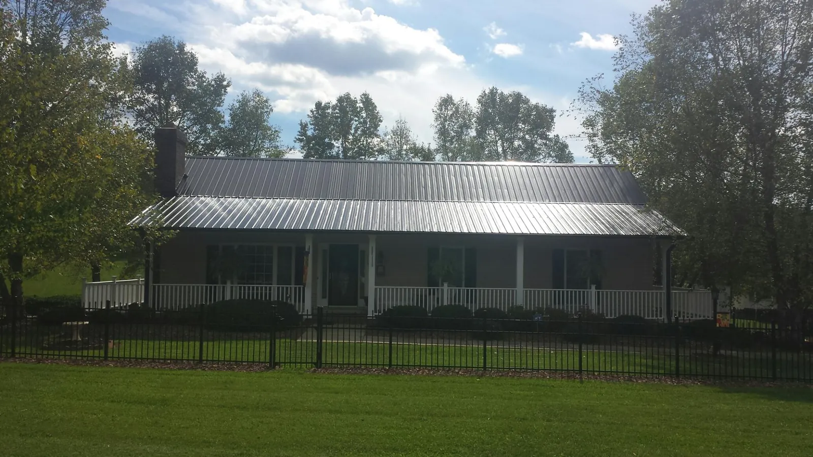 Gray metal roof on a brick ranch with a full width front porch — Gutter Guard Installation work by our crew in Hooks